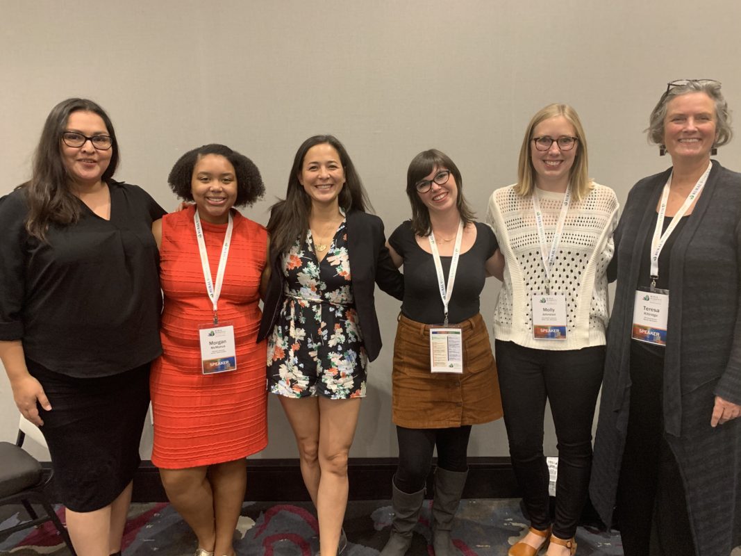 A picture of six women smiling together at a conference.