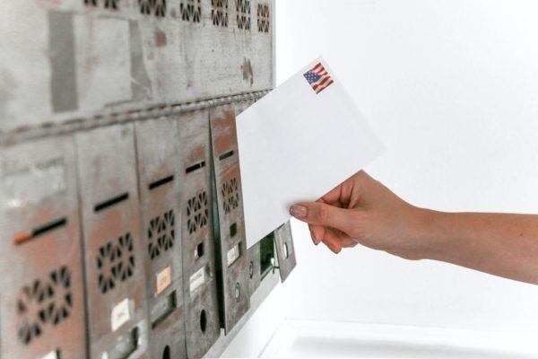 A picture of a person placing and envelope in a mailbox.