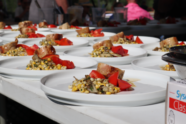 A picture of fancy dishes featuring corn, tomato, and pork.