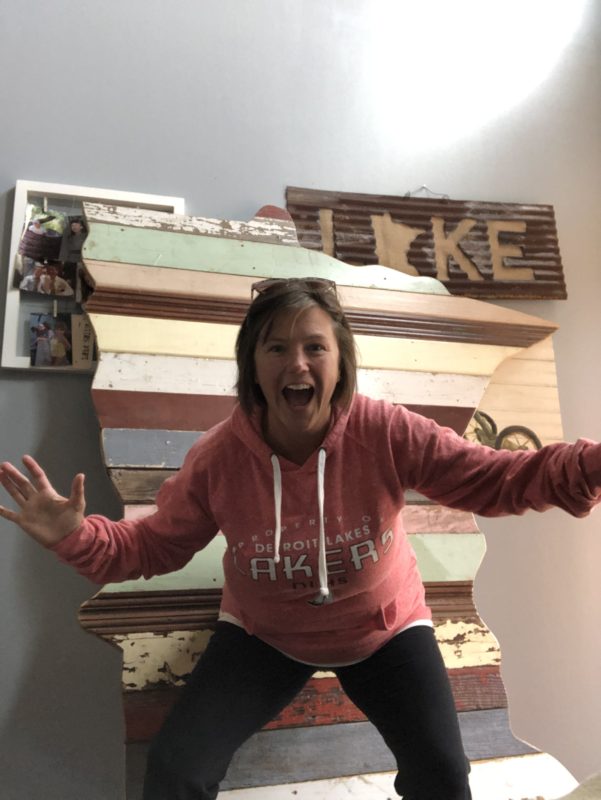 A picture of an excited woman standing in front a bunch of Minnesota signs.