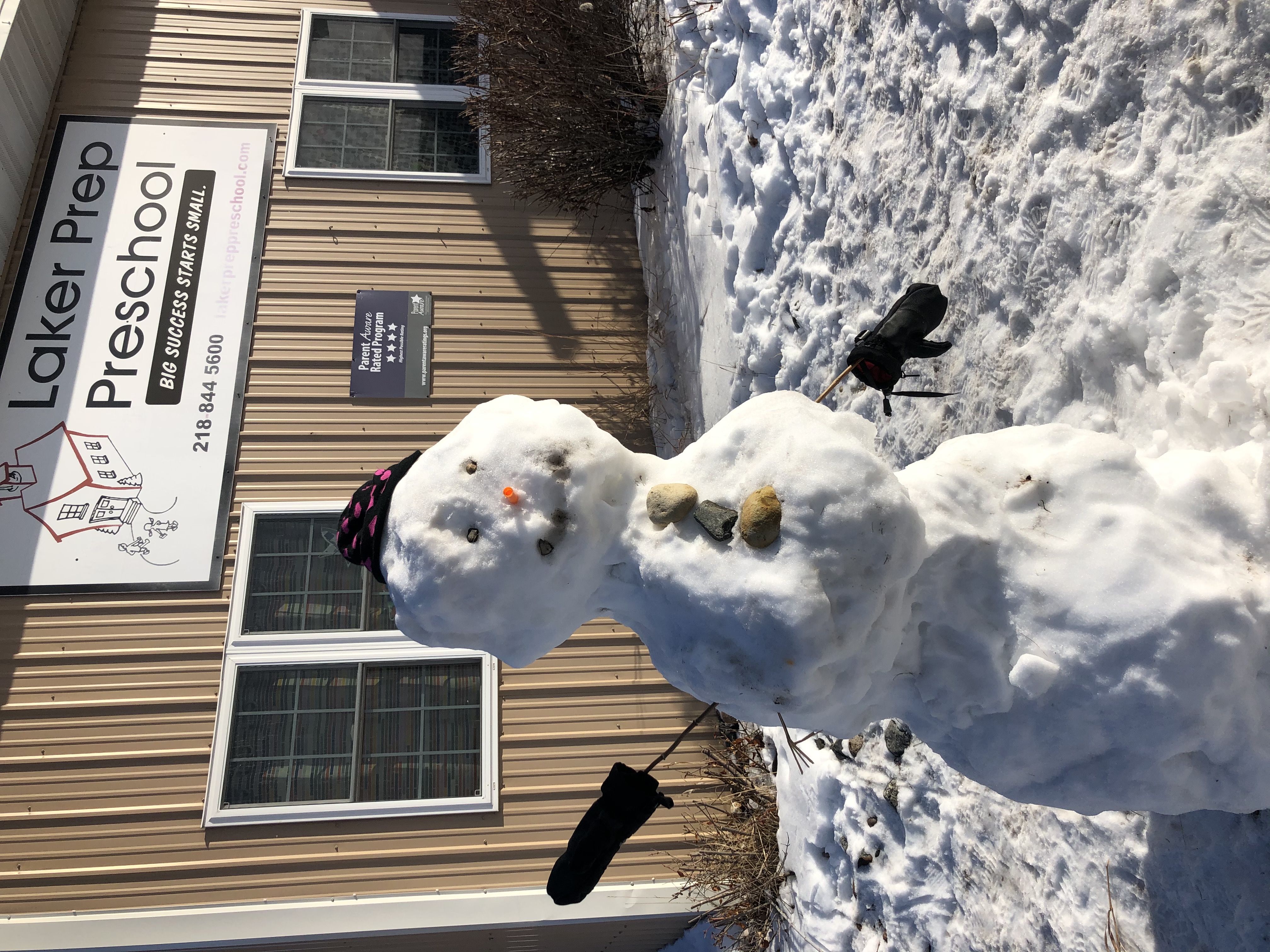 A picture of a snowman in front of a preschool.