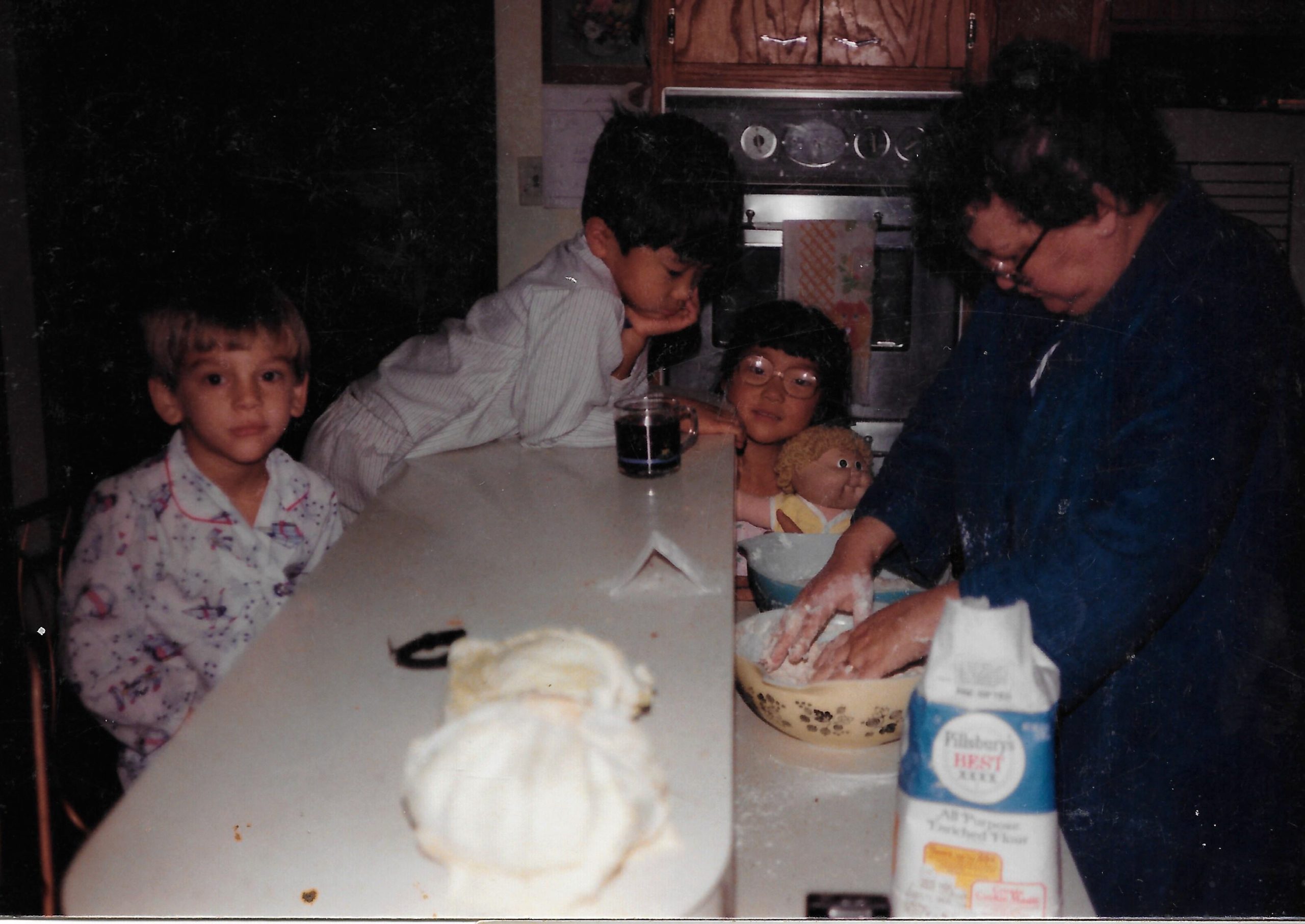 A picture of a grandma baking with her three grandchilden.