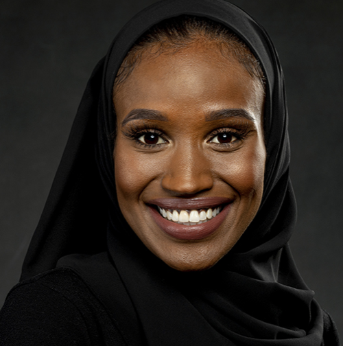 A picture of a woman smiling wearing a black head covering.