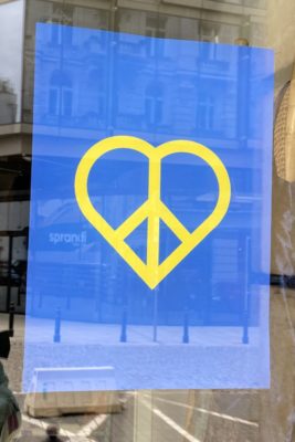 Using the colors of the Ukrainian flag, a heart is made with an intersecting peace sign.