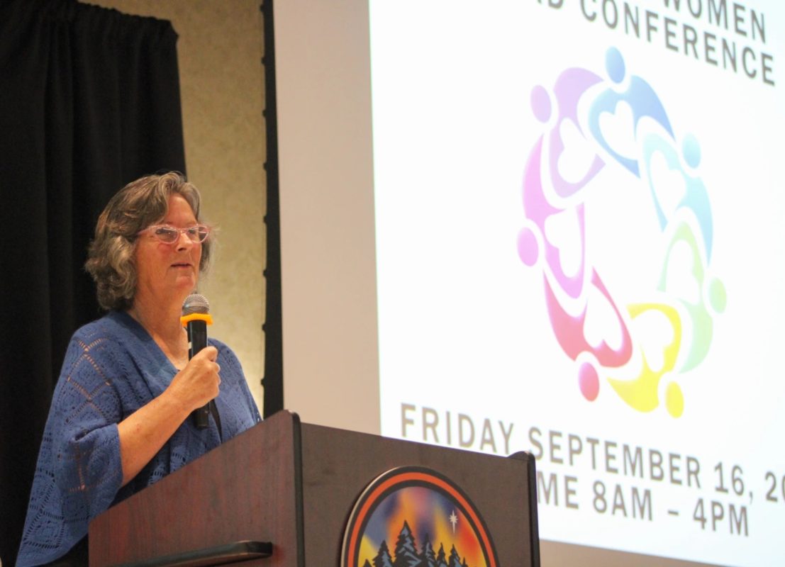 A picture of the founder of 100 Rural Women, Teresa Kittridge, speaking at the Empowering Women to Lead Conference in Walker, MN on Sept. 16, 2022. She is wearing a blue blouse and glasses, with short grey hair.