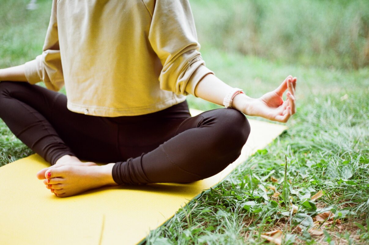 A picture of a woman wearing leggings and a yellow top doing yoga.