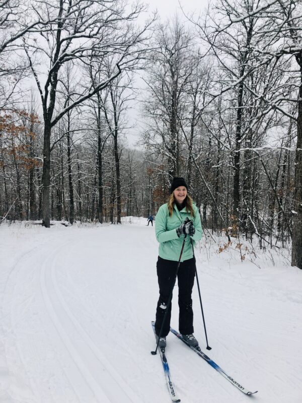 Erica smiles while cross country skiing in the woods