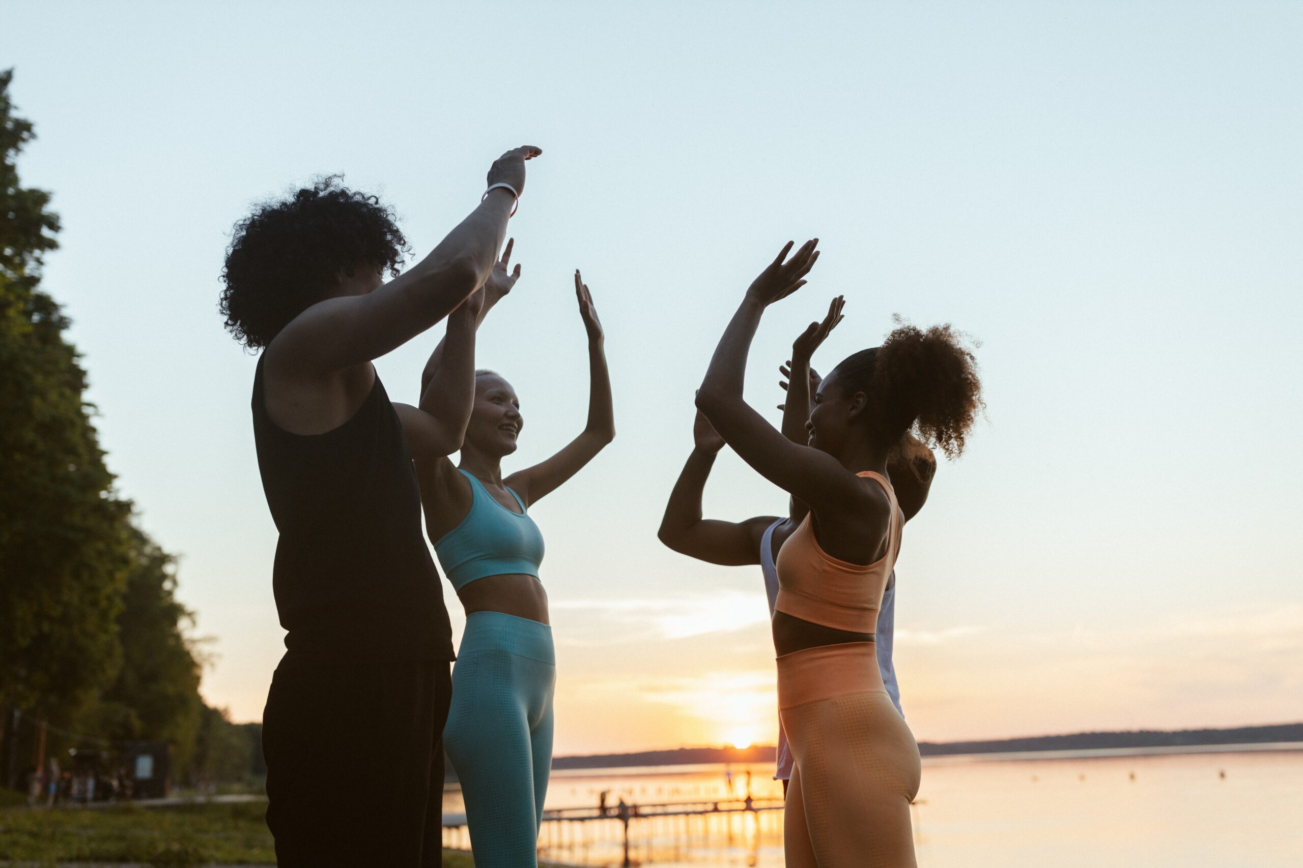 Four women high-fiving outside in athletic attire